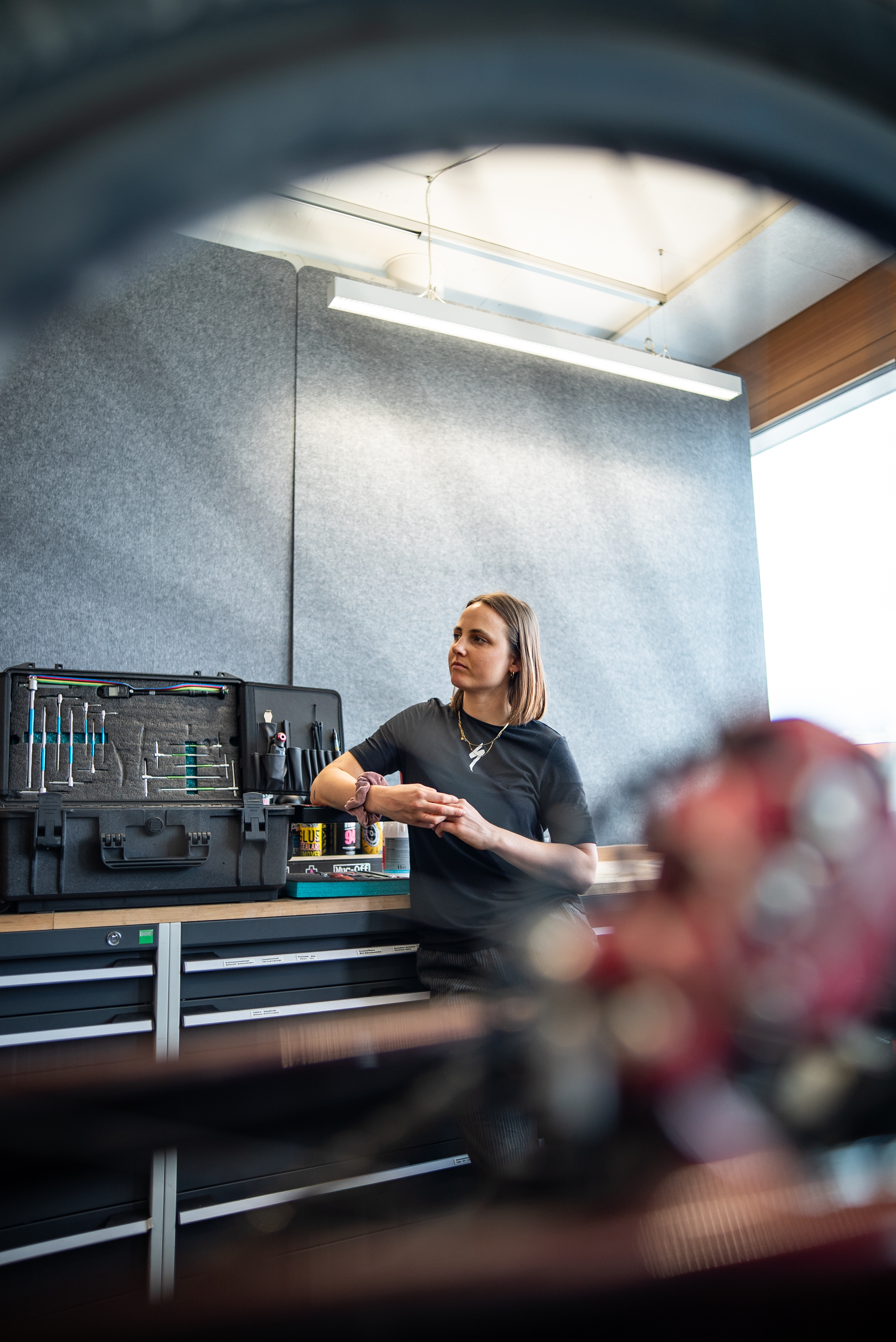 Sofia Wiedenroth steht in einer Werkstatt vor einem geöffneten Werkzeugkoffer auf einer Werkbank. Im Vordergrund ist unscharf ein Fahrradteil zu erkennen.